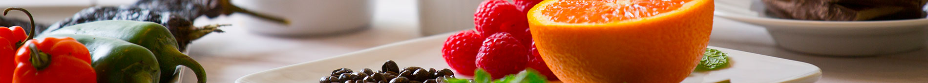 Various fruit and jalapenos and chilis sit on white plates.